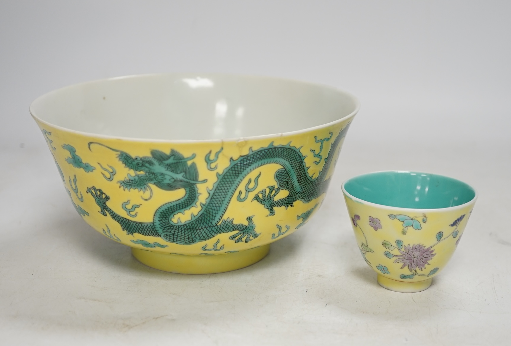 A Chinese yellow ground 'dragon' bowl, probably late Qing dynasty, and a similar floral cup, bowl 9cm high, 18.5cm diameter. Condition - bowl has a large section restored